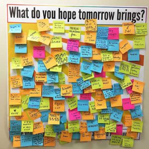 Prompt poster for "What do you hope tomorrow brings?" with sticky note comments from patrons.