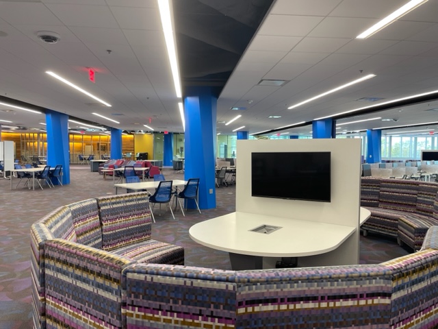 Photograph of a circular seating arrangement surrounding a large screen monitor on the third floor of the John C Hitt Library.