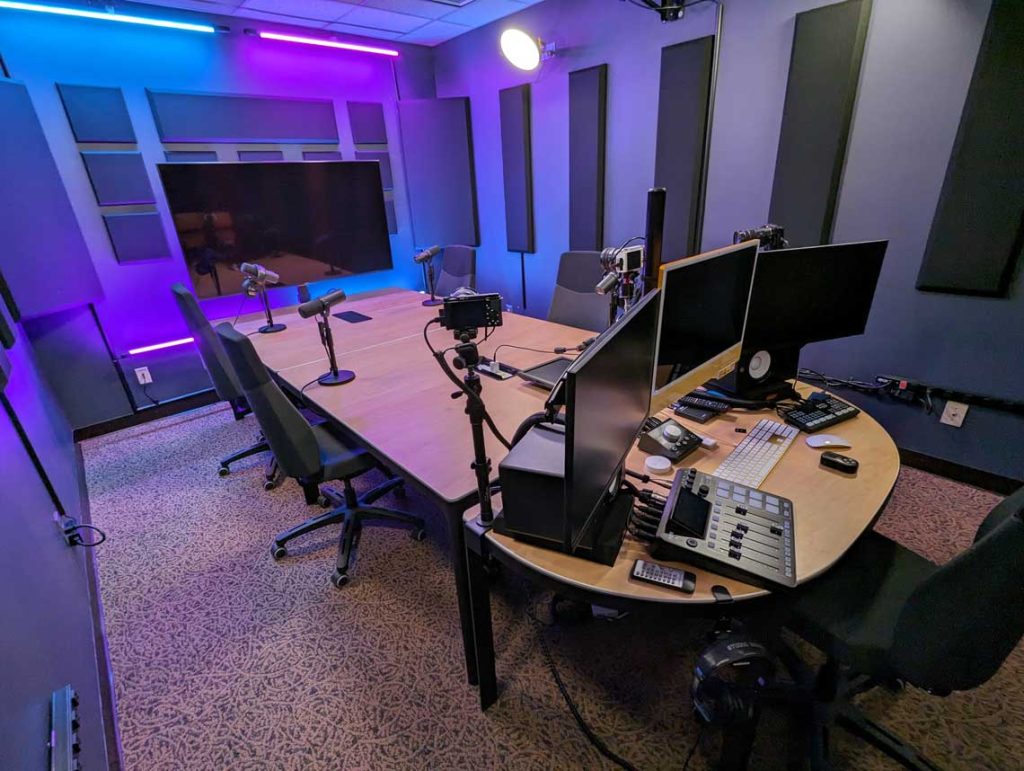 Hitt Maker Podcast Studio showing engineer equipment and chairs with microphones at a table