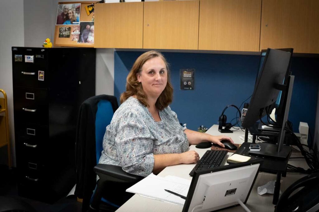 Woman working at her desk in a modern office, focused on her computer during a typical weekday morning.