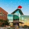 Entrance of the Student Union side of the John C. Hitt Library with a santa hat and snow falling.