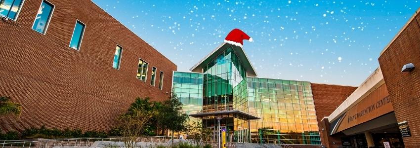 Entrance of the Student Union side of the John C. Hitt Library with a santa hat and snow falling.