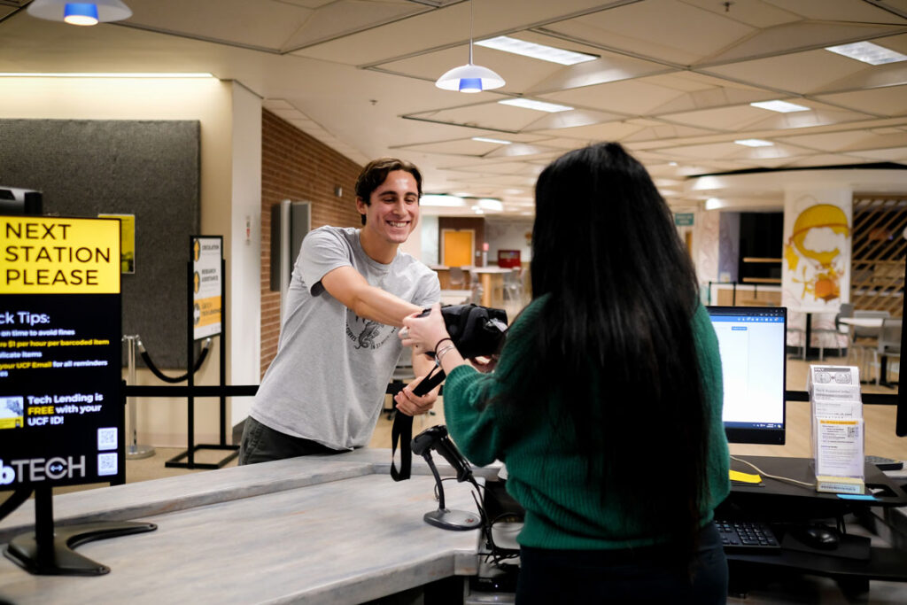 A student recieving a technology checkout item from a LibTech employee at the LibTech  Technology Lending desk.