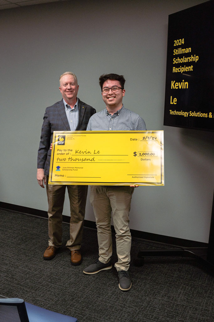 Dean Beau Case giving staff member Kevin Le a scholarship check for $2000.