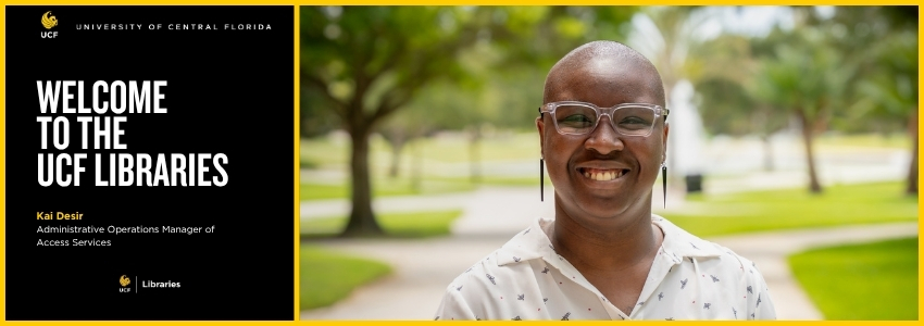Smiling person standing on a college campus with green trees and grass and a fountain in the background.