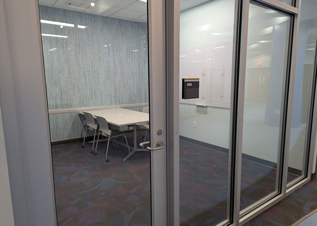 Study room with a rectangular table and four chairs on caster wheels with whiteboard mounted on the wall.