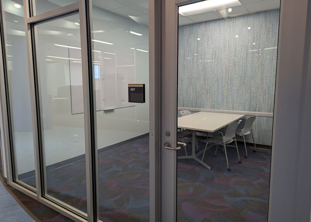 Study room with a rectangular table and four chairs on caster wheels with whiteboard mounted on the wall.