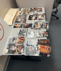 A desk covered with stacks of black-and-white and color photographs depicting cultural events and gatherings held by UCF's International Student Association.