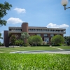 The John C. Hitt library building with green grass in the foreground and blue skies in the background.