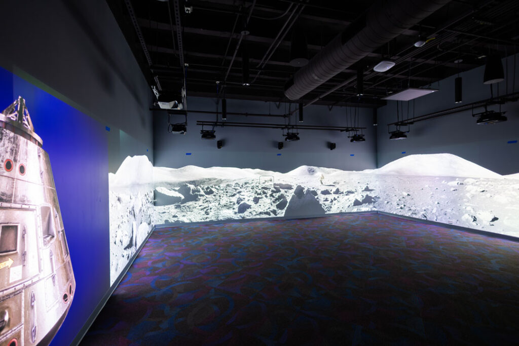 Open room with immersive images projected onto the walls surrounding the viewer in 270 degree view.