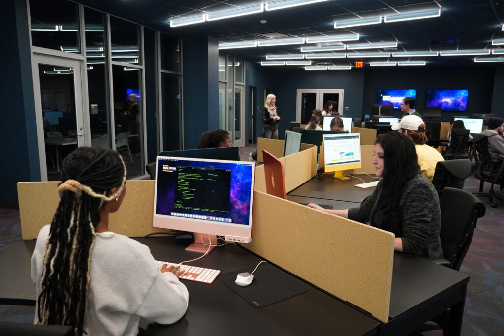 An open area filled with students sitting at computer work stations.