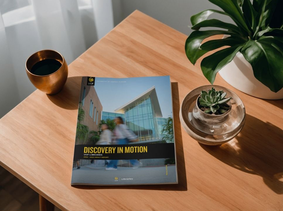 Magazine cover sits on a wooden table with a cup of coffee and a plant next to it. 